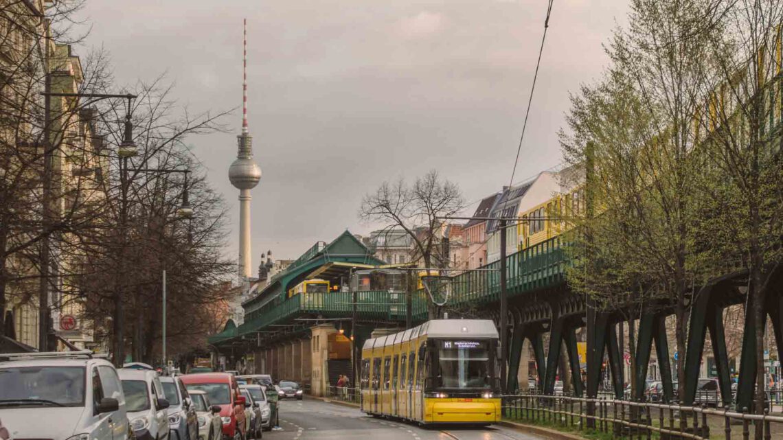 Im Vordergrund Straße mit Autos, Tram, U-Bahn in Berlin Kreuzberg. Im Hintergrund Fernsehturm